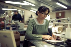 Worker in textile industry sewing on machine